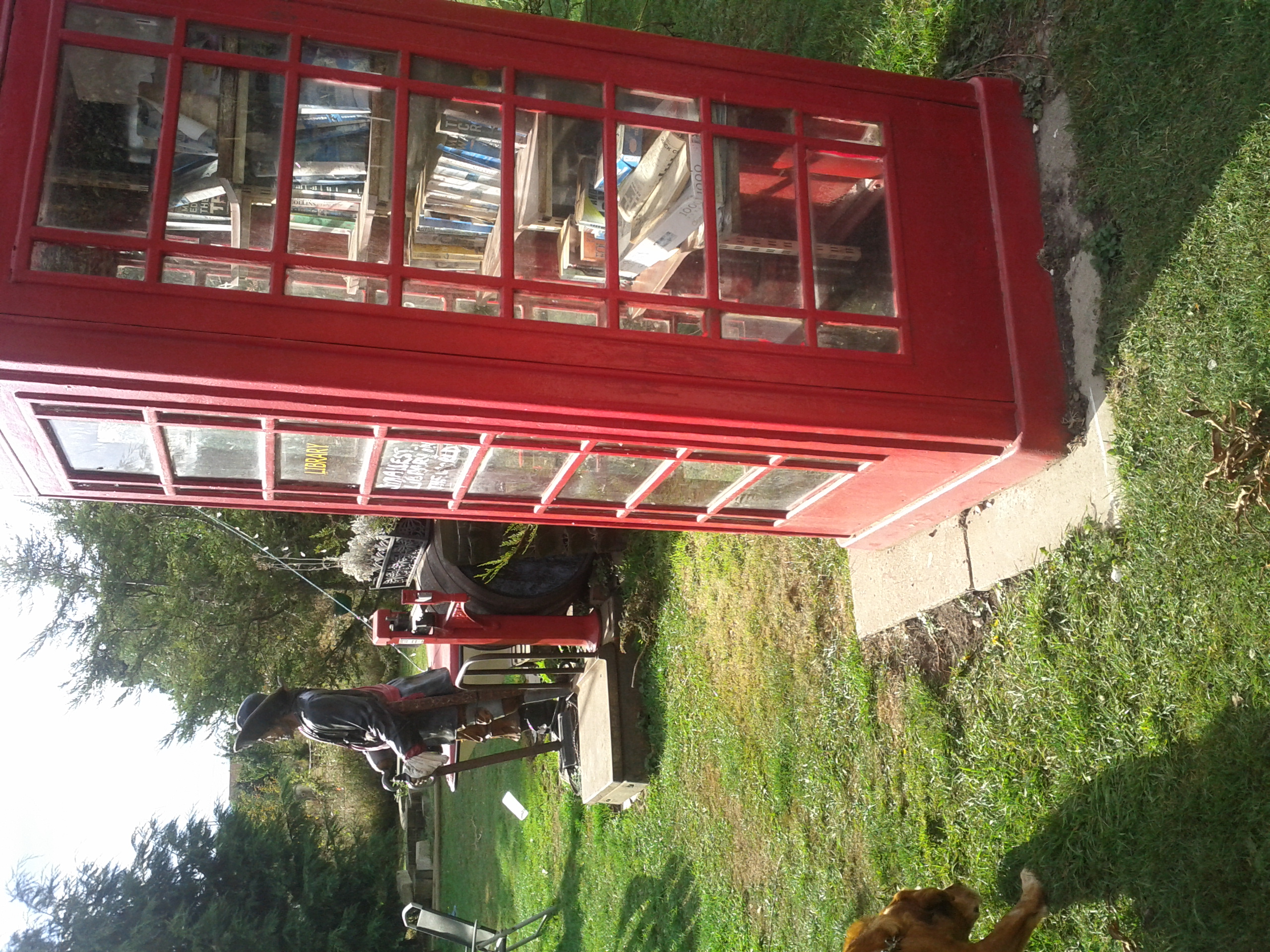 Sideways photo of a red telephone box on grass