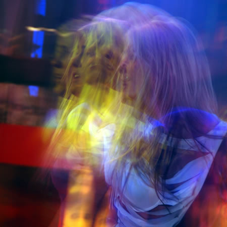 A blurred, multiple exposure colourful shot of a person with long hair in blue and yellow light