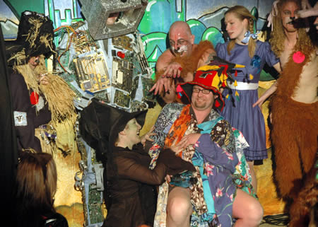 Costumed cast of a panto on stage including a scarecrow, a lion and a child in a blue dress
