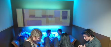 A group of people sit on sofas in a room lit with blue light