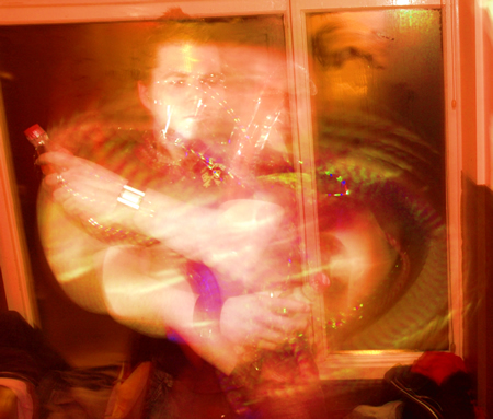 Heavily blurred person in an orange-lit window with arms crossed