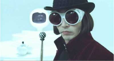 Person in a black bowler hat, white goggles and a dark red coat, with a striped staff beside them