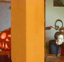 Orange pillar with a glowing carved pumpkin on the left and a child looking out on the right