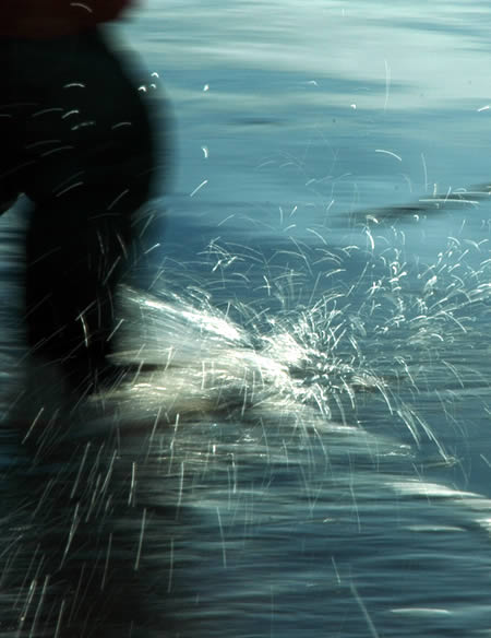 Blurred dark figure beside choppy water with spray flying