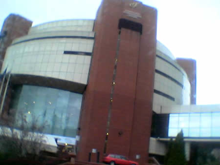 A curved glass and red brick conference centre building under a pale sky