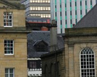 Old stone buildings with arched windows and taller modern blocks behind them