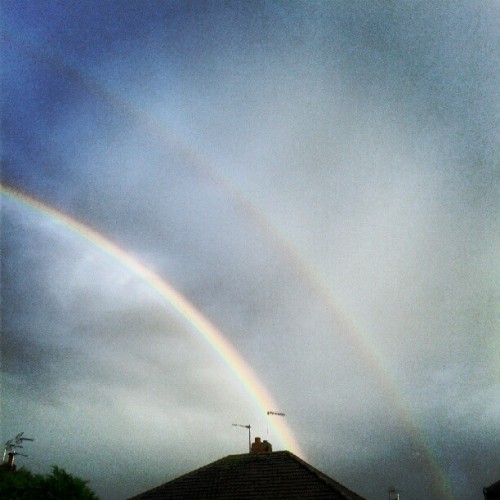 Double rainbow across a grey sky above a rooftop