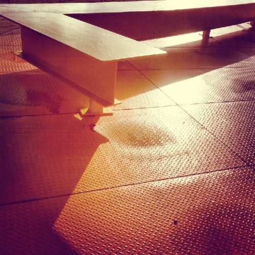 Angled yellow and orange metal structure on a steel plate floor, seen in warm light
