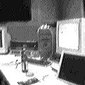 A desk with a computer monitor and bottles, black-and-white