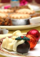 Mince pies on a plate above a chocolate Christmas pudding decoration and red baubles